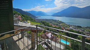 Un balcón con vista a un lago, montañas y un pueblo abajo.