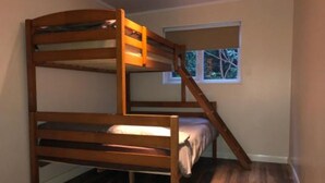 A bunk bed in a room with wooden flooring and a window with a view of trees. - Cosy Cabin (Finchampstead)