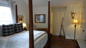 Habitación de hotel con cama con dosel, lámpara de pie, un cuadro en la pared y una puerta decorada con un cráneo de toro.