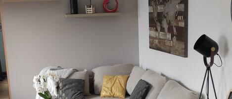 A modern living room with a sofa, coffee table, and a dining area with a table and chairs.