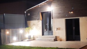 Un bâtiment à la façade sombre, doté d’une entrée bien visible et d’un éclairage extérieur soigné.