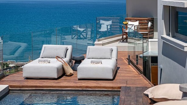 Ein Poolbereich mit Liegestühlen und Blick auf das Meer.