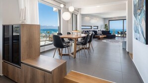 Ein modernes Wohnzimmer mit einem großen Esstisch, schwarzen Stühlen und einem eingebauten Fernseher.