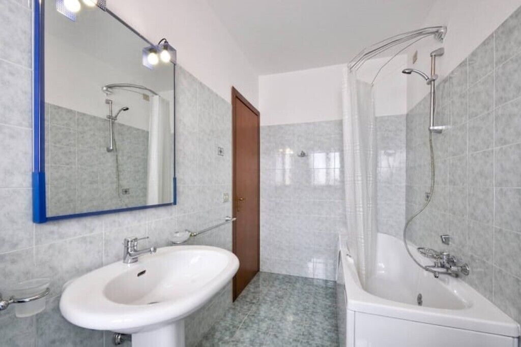 Une salle de bain équipée d’un lavabo, d’un miroir, d’une douche et de toilettes.