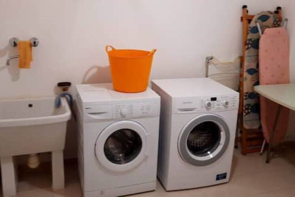 A laundry area with two washing machines and a sink.