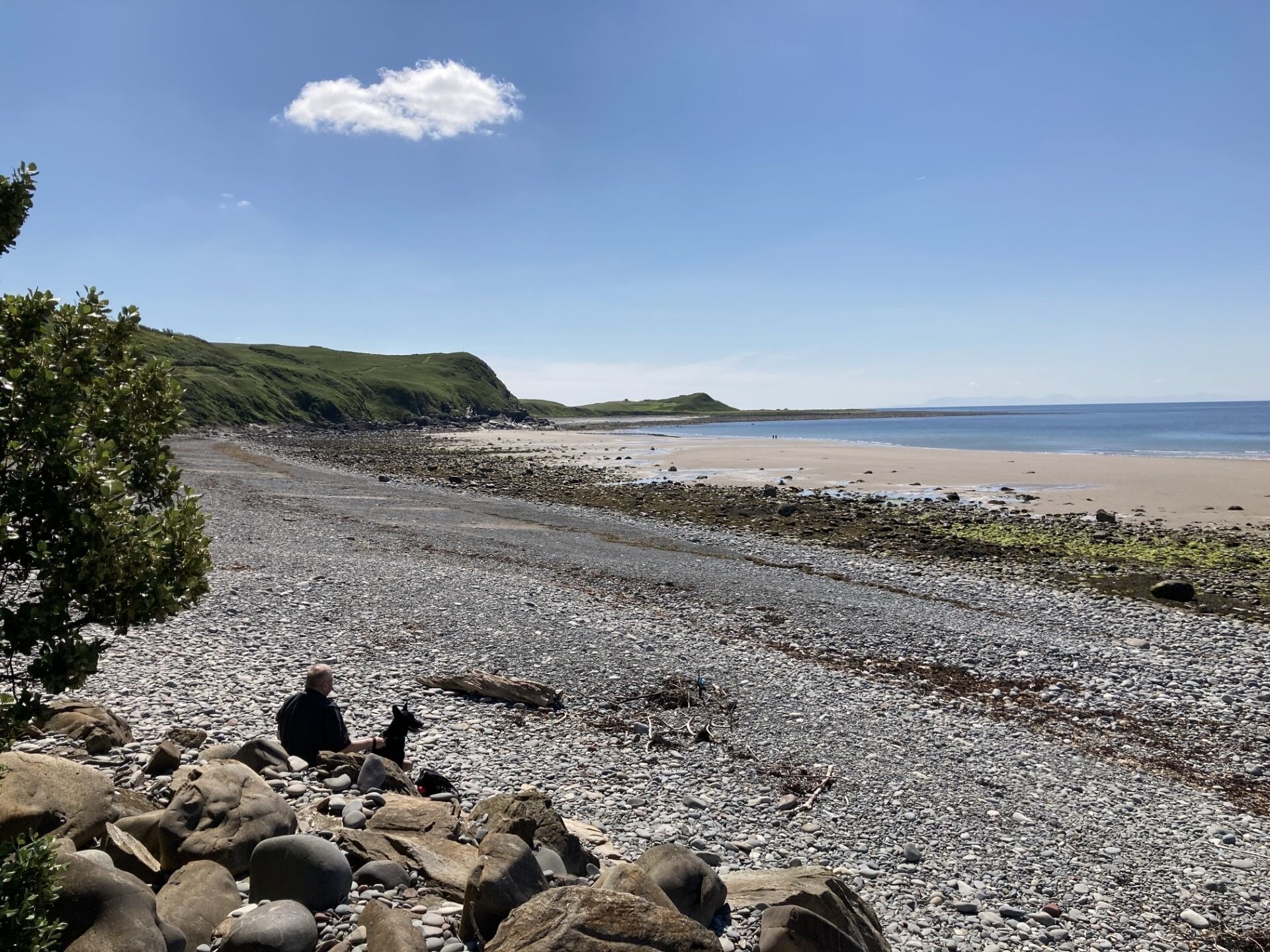A rocky beach with a clear sky and distant hills.
