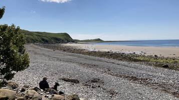 A rocky beach with a clear sky and distant hills.