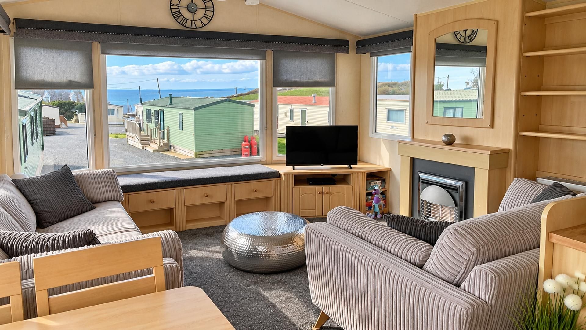 Interior acogedor de una autocaravana con sofá, una mesita, televisor y chimenea.