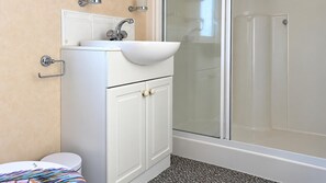 Een badkamer met een wit wastafelmeubel, toilet en een douchecabine met glazen wanden.