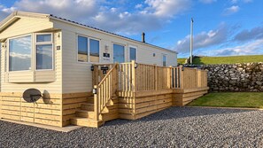 Een caravan met een houten terras en een trap die leidt naar een deur met daarop '40 Salisbury'.