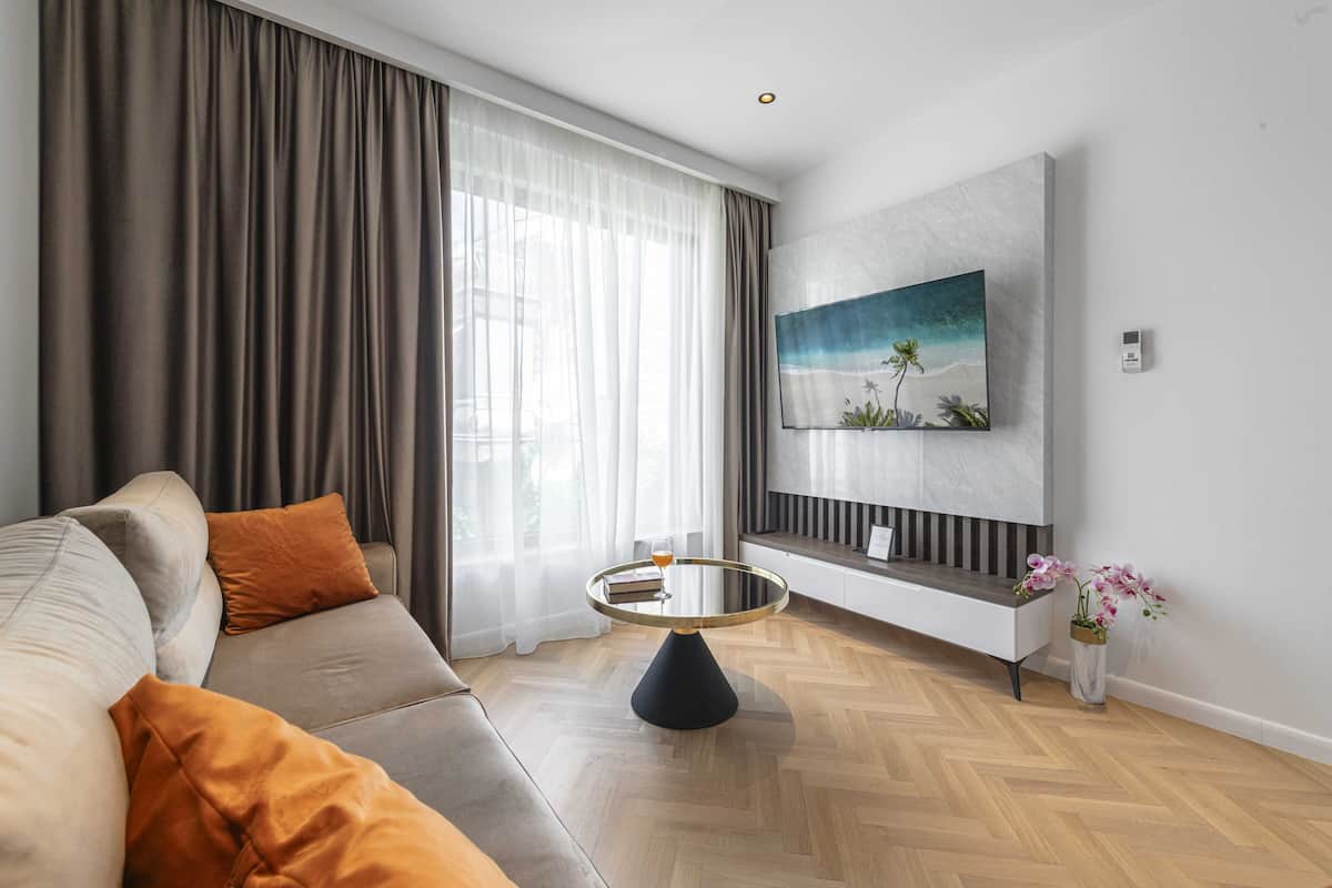 Un salon moderne avec un canapé, une table basse ronde, un tableau au mur et un vase rempli de fleurs.