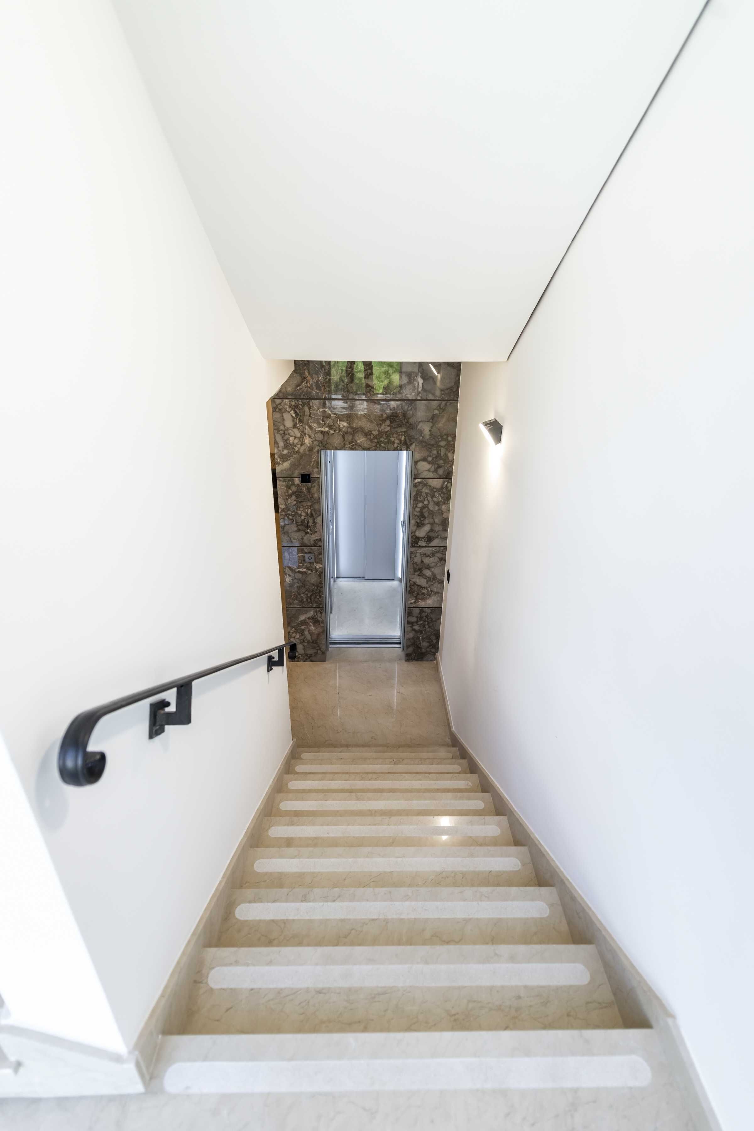 A modern staircase with a stone wall and a door at the top.