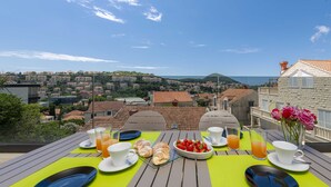 A table set for breakfast with a scenic view of a coastal town. - Rausion Luxury Apartments (Dubrovnik)