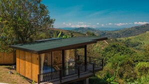 Una cabaña moderna de madera con balcón y vistas a un valle exuberante.
