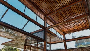 Un interior arquitectónico moderno con techo de madera, ventanas amplias y elementos decorativos colgantes.