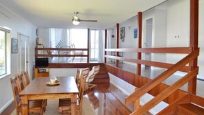 Un coin repas avec une table et des chaises en bois, un téléviseur et un escalier avec des rampes en bois.