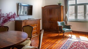 Un coin repas avec une table en bois, des chaises, un buffet et un téléviseur fixé au mur.
