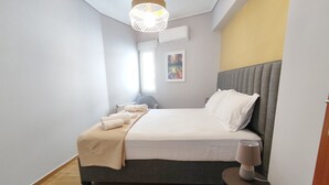 Une chambre à coucher bien rangée, avec un lit, une table de chevet et un luminaire suspendu.