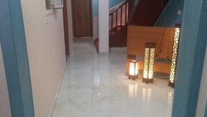 Un pasillo con suelo de mármol, una escalera y apliques decorativos en la pared.