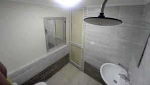 Un baño pequeño con ducha, lavamanos y espejo.