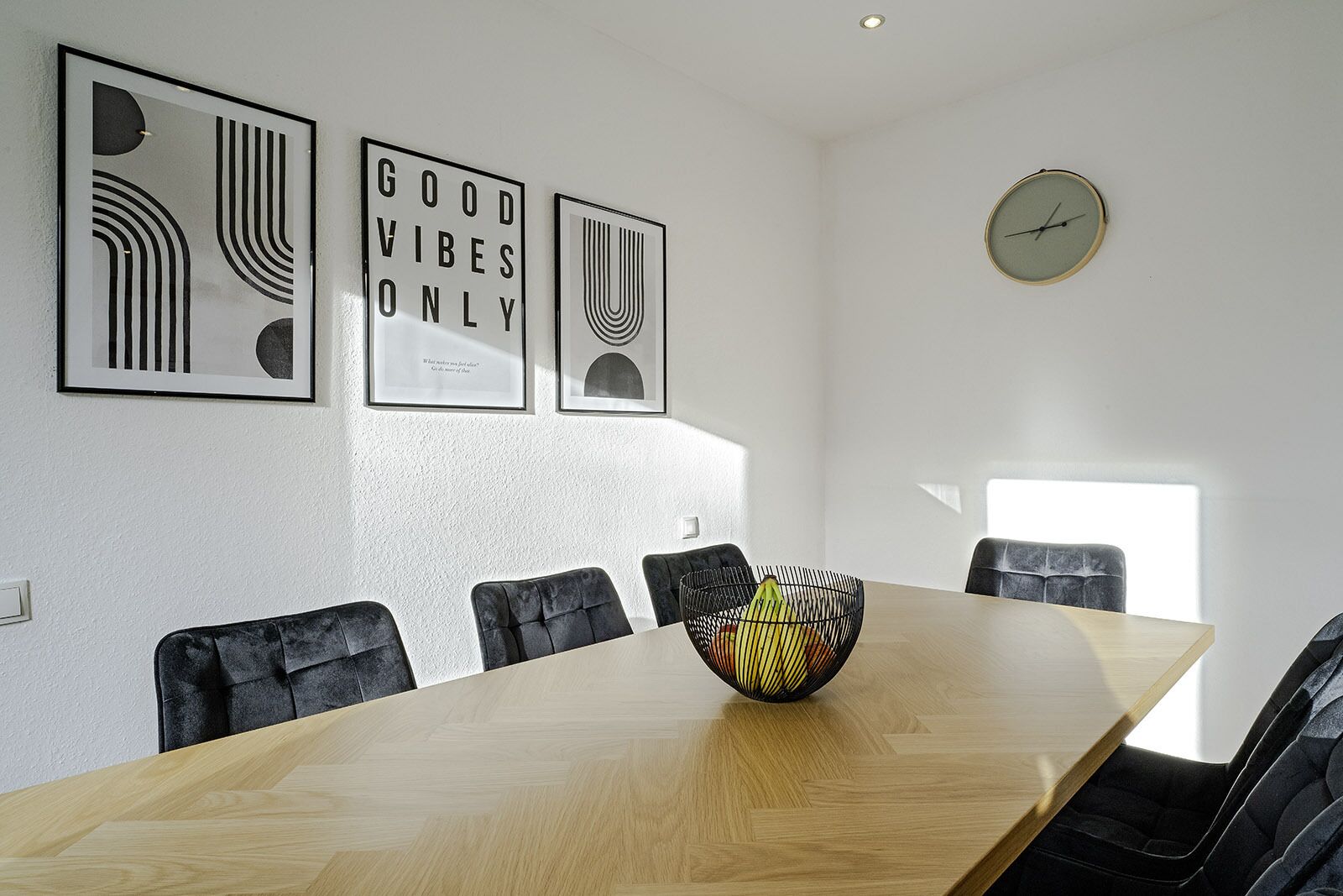 A conference room with a long table, six chairs, and three framed artworks on the wall.