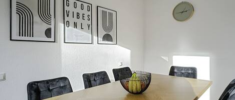 A conference room with a long table, six chairs, and three framed artworks on the wall.