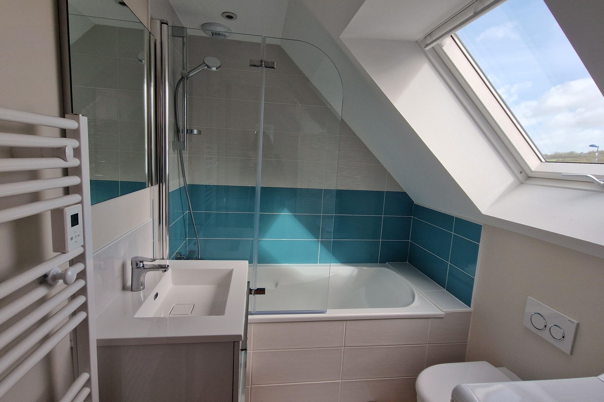 A modern bathroom with a skylight, a bathtub, and a sink.