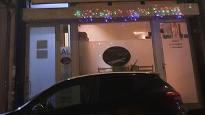Un immeuble à plusieurs étages, avec des fenêtres illuminées et une voiture garée devant.