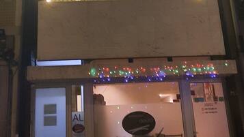 Un immeuble à plusieurs étages, avec des fenêtres illuminées et une voiture garée devant.