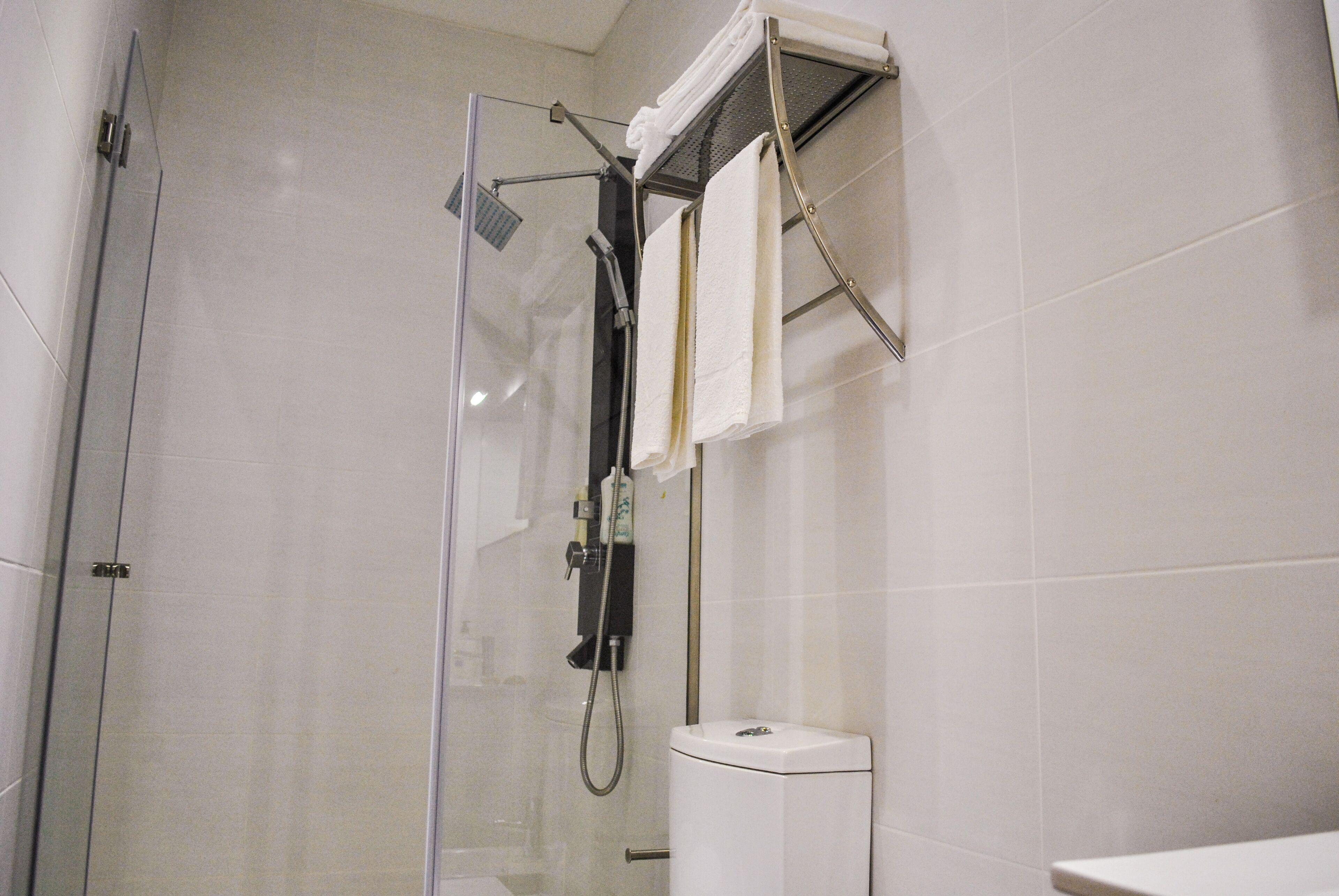 A modern bathroom with a glass-enclosed shower, a white toilet, and a towel rack.