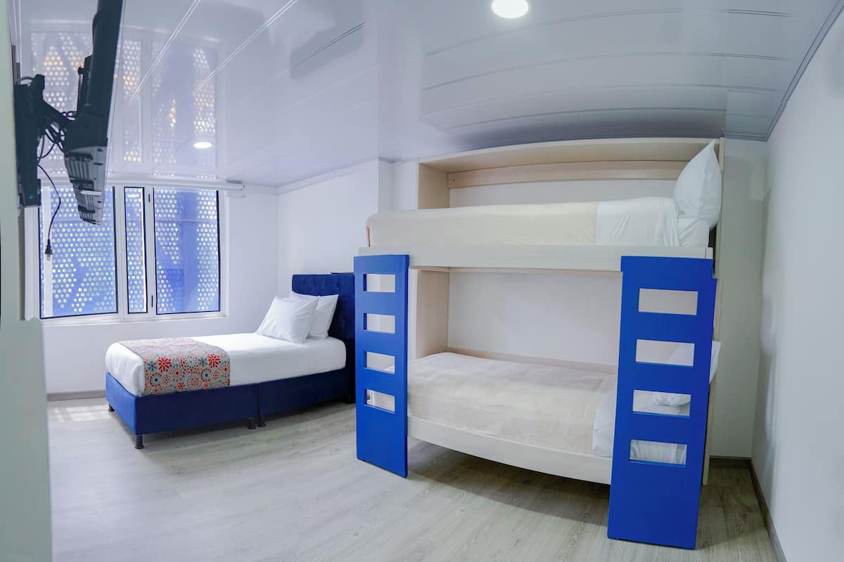 Une chambre avec un lit superposé, une fenêtre, un bureau et une chaise.