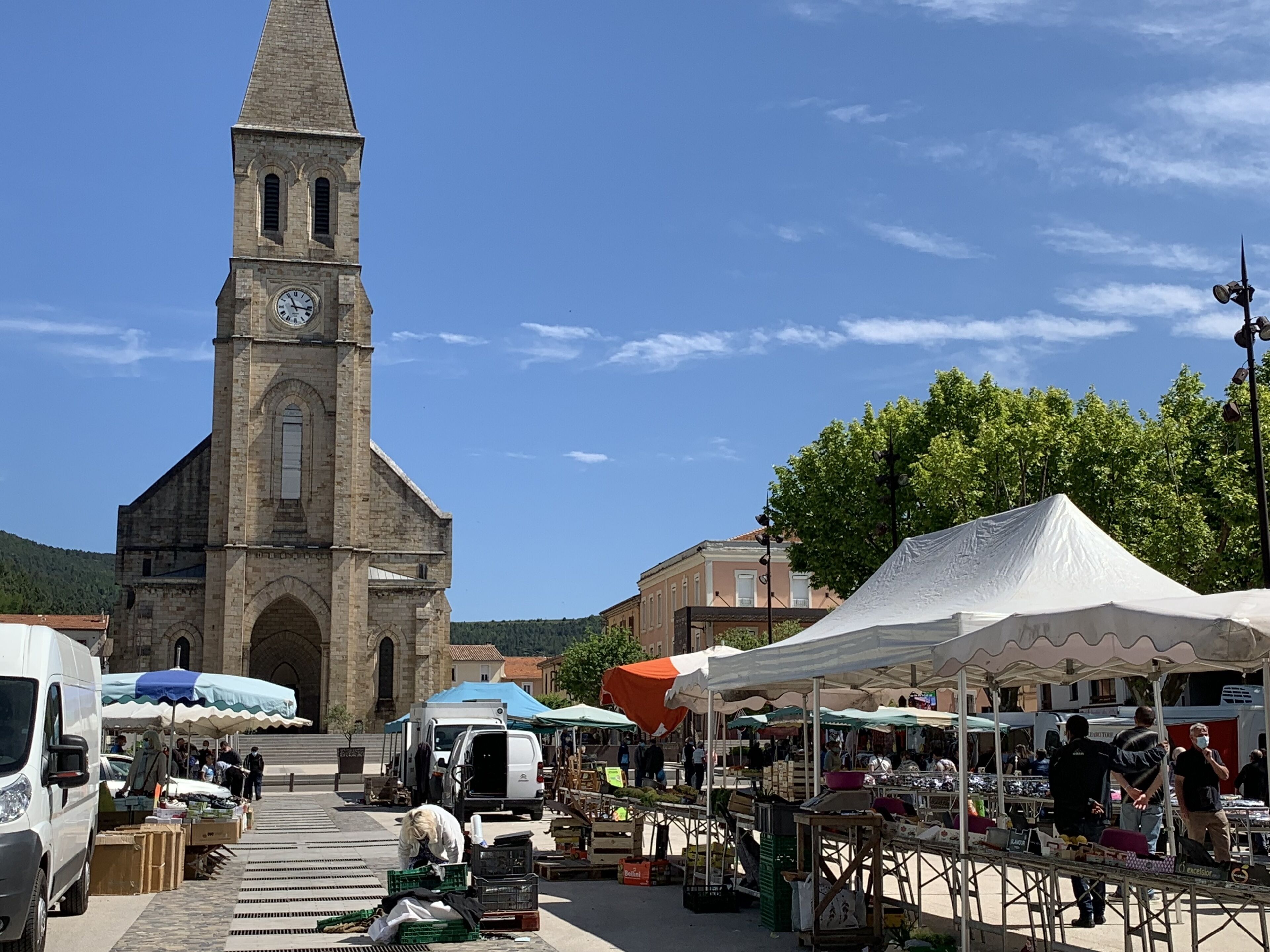 A market area with stalls and a church with a clock tower.