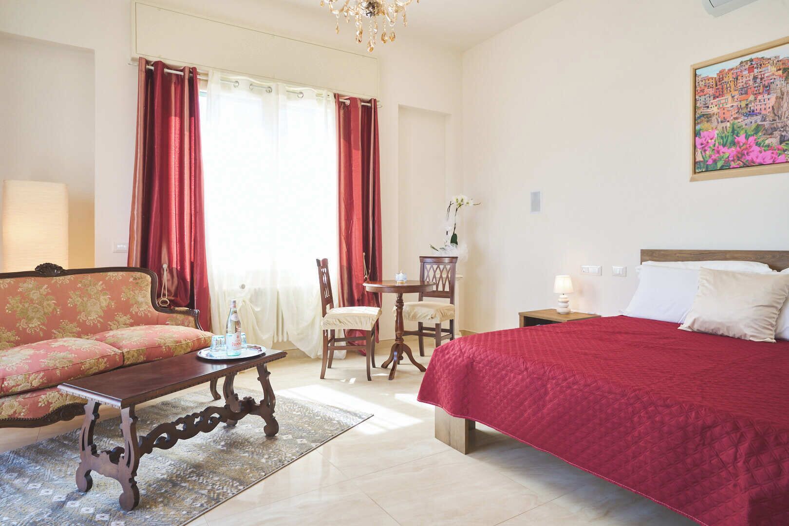 A hotel room with a bed, a sofa, a dining table, and a chair.