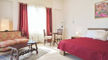A hotel room with a bed, a sofa, a dining table, and a chair.