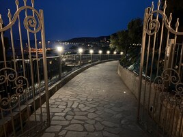 Un camino de piedra que lleva a una entrada con puerta de hierro forjado decorativa.