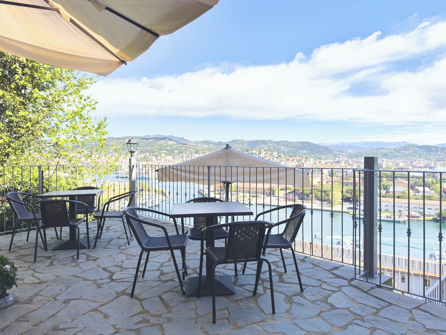 A terrace with stone flooring, outdoor furniture, and a view of a city and river.