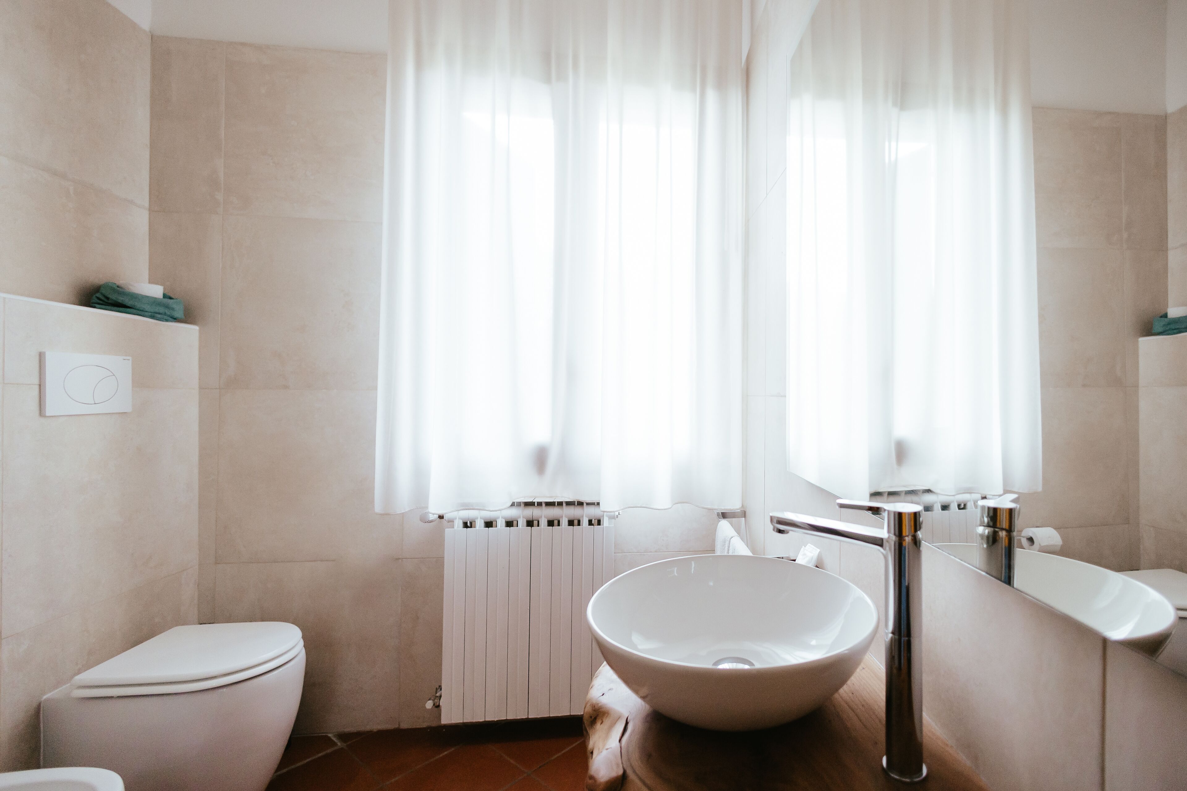Un baño moderno con inodoro blanco, un lavabo grande en blanco y un espejo sobre el lavabo.