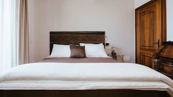 Una cama bien hecha con cabecera de madera, ropa de cama blanca y una sola almohada marrón.