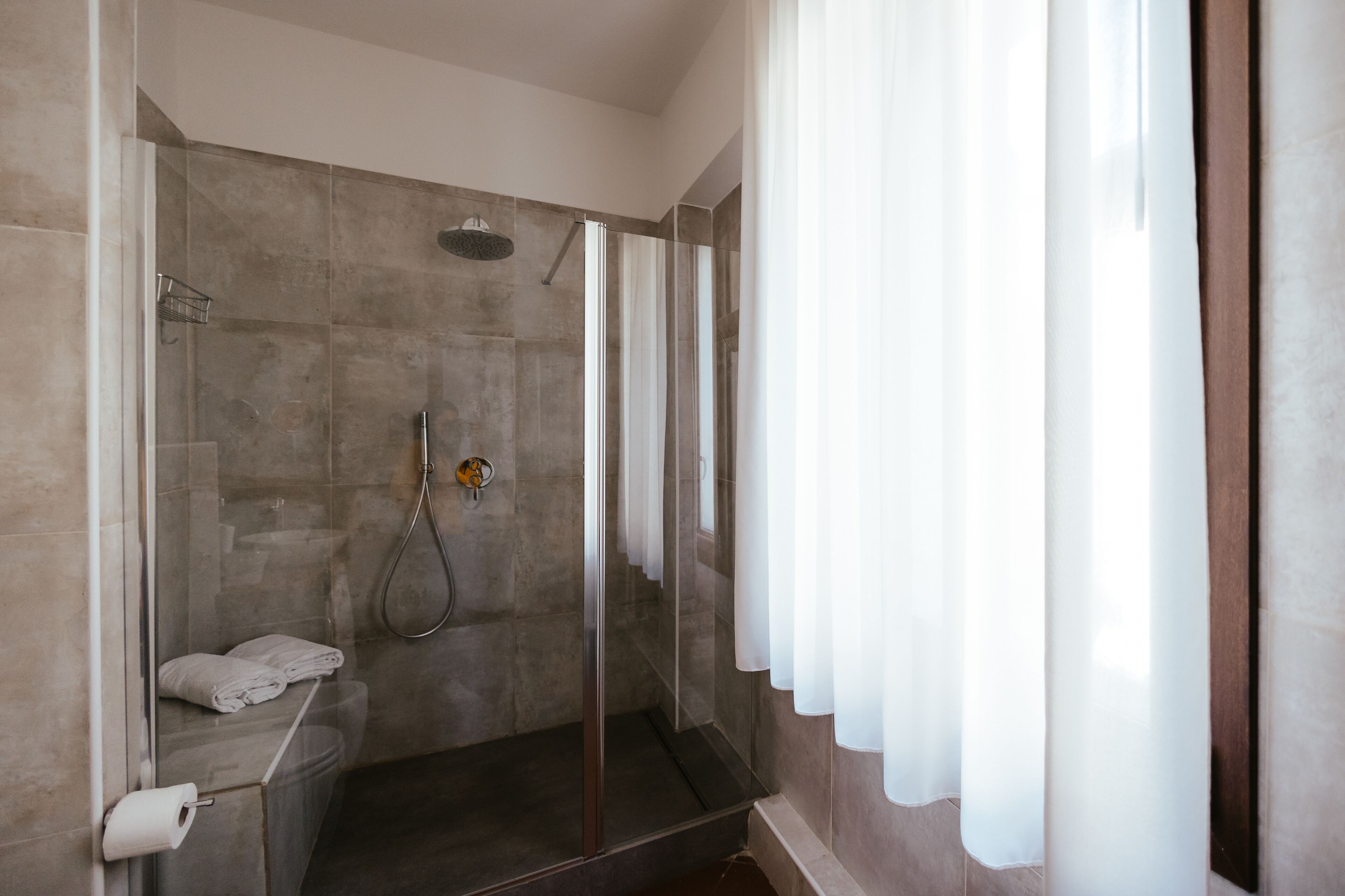 A modern shower with a glass door, a towel rack, and a showerhead.