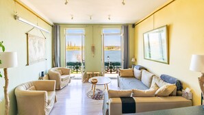 A spacious living room with two sofas, a coffee table, and a view of the sea through large windows.