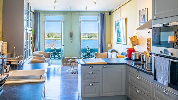 A modern kitchen with a large island, built-in oven, and a view of the outdoors.