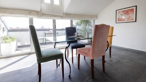 A modern room with a glass table, four chairs, a large window, and a painting on the wall. - Italianway Comfort - Vigevano 7 (Milan)