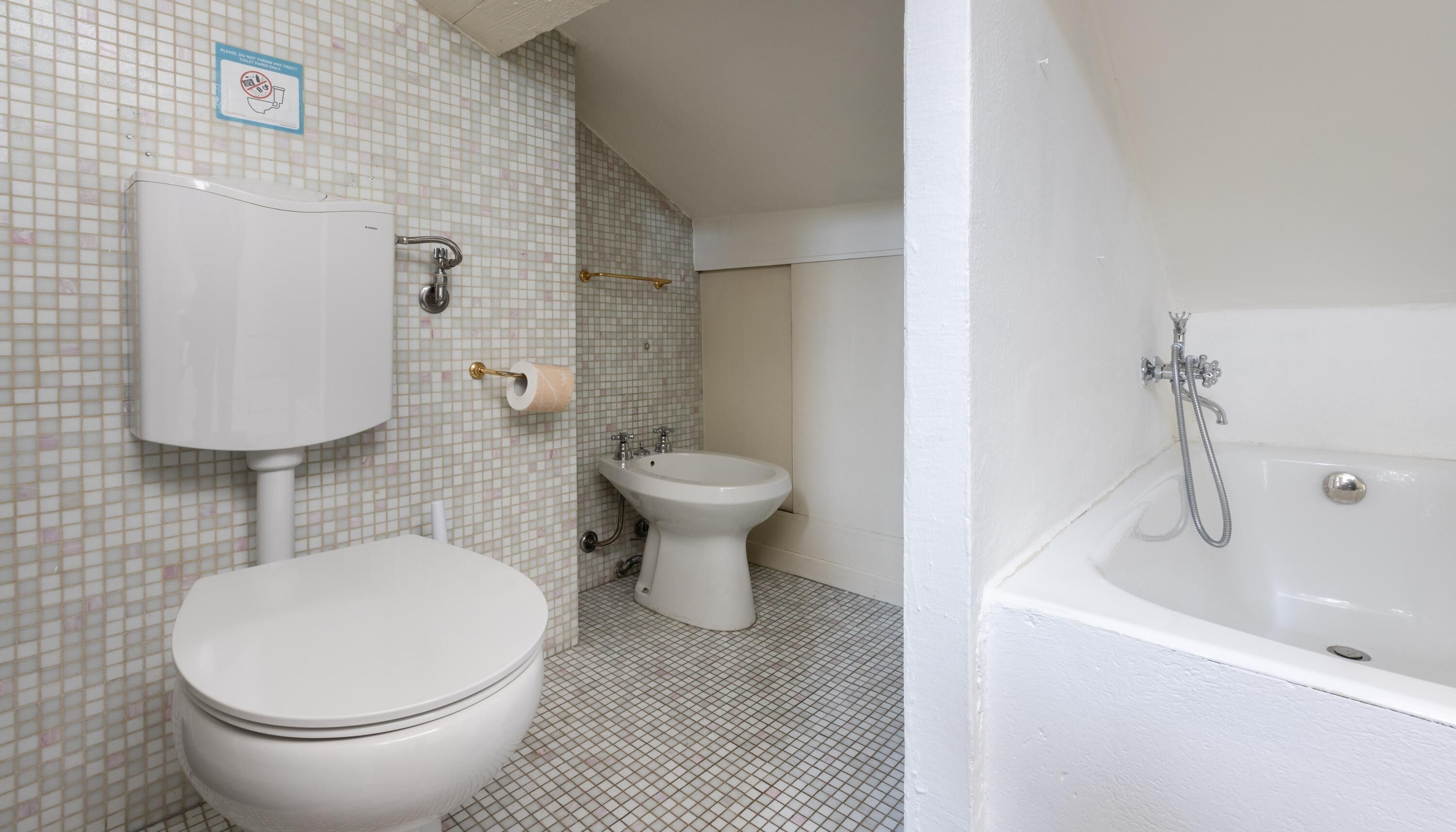 A bathroom with a toilet, bidet, and bathtub.