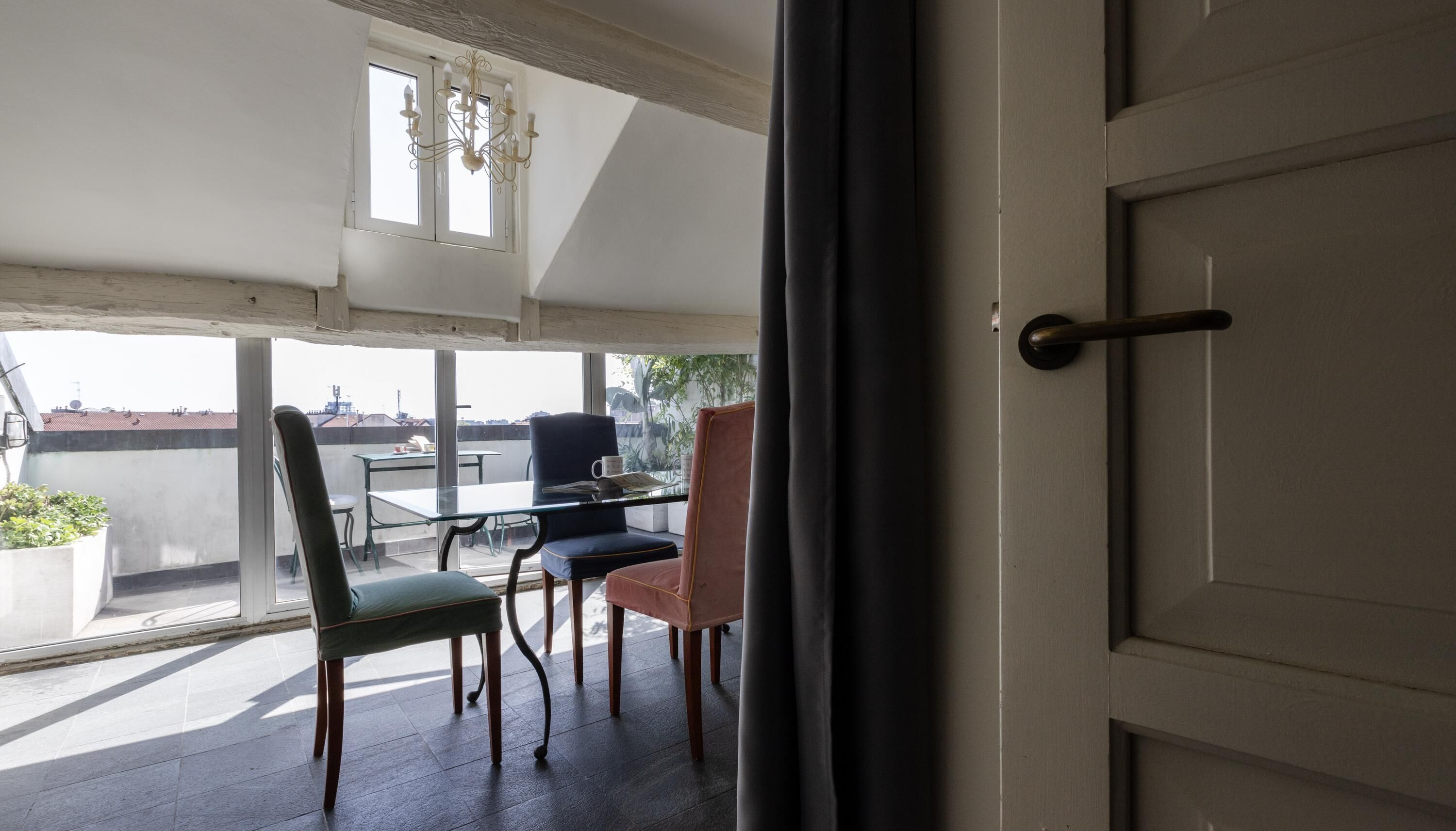 A balcony with a table and chairs, a chandelier, and a view of buildings.