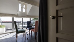 A balcony with a table and chairs, a chandelier, and a view of buildings. - Italianway Comfort - Vigevano 7 (Milan)