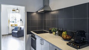 A modern kitchen with dark tiles, a stove, a sink, and a countertop with various items.