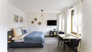 A modern bedroom with a bed, bedside table, and a desk with a chair.