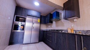 Uma cozinha moderna com armários escuros, eletrodomésticos de aço inoxidável e bancada de granito.