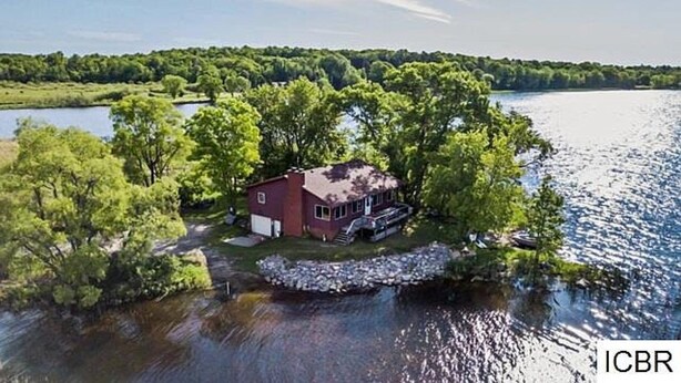 Ett hus som är omgivet av vatten och har en brygga, och som dessutom är inbäddat i träd.