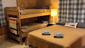 A bunk bed room with a wooden headboard, a wall-mounted fish decoration, a checkered curtain, and a bedside lamp.